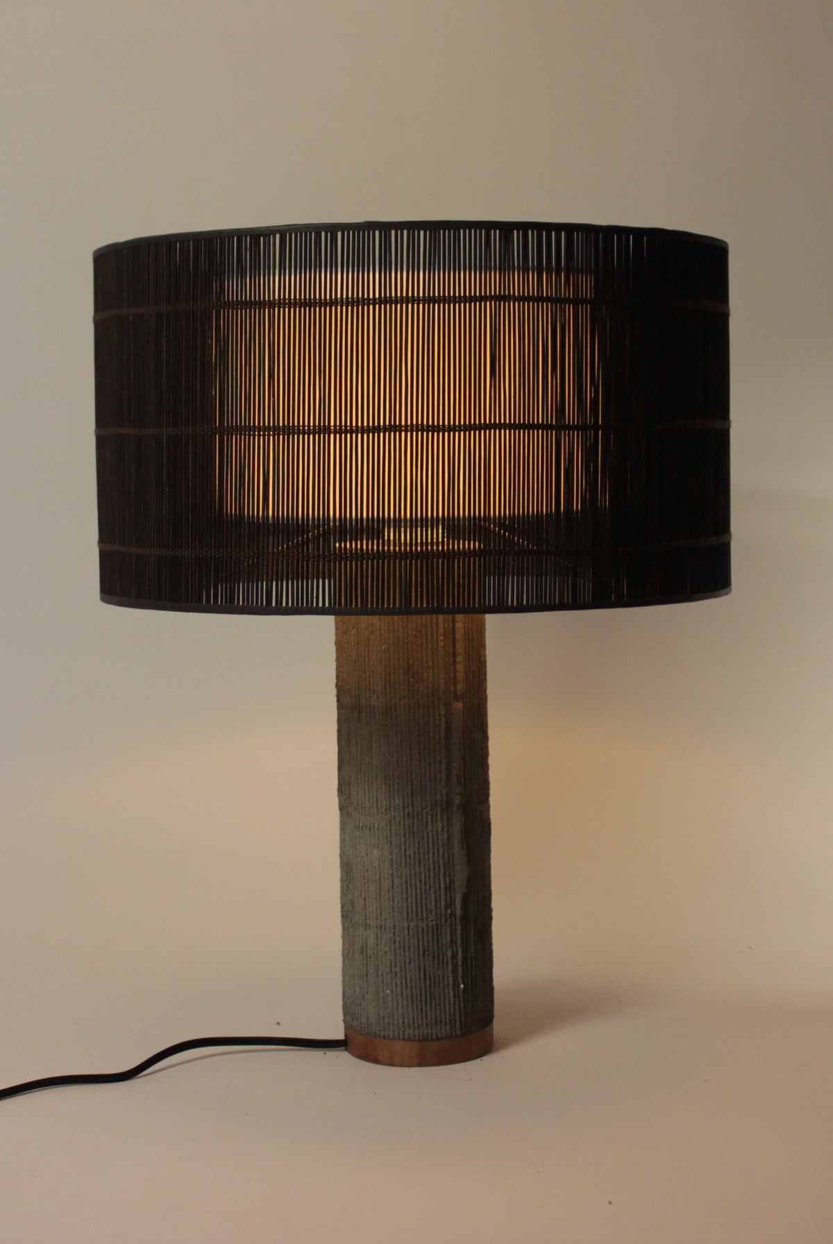 Stijlvolle lamp met donkerbruine geweven kap en betonnen voet in rustige tint.