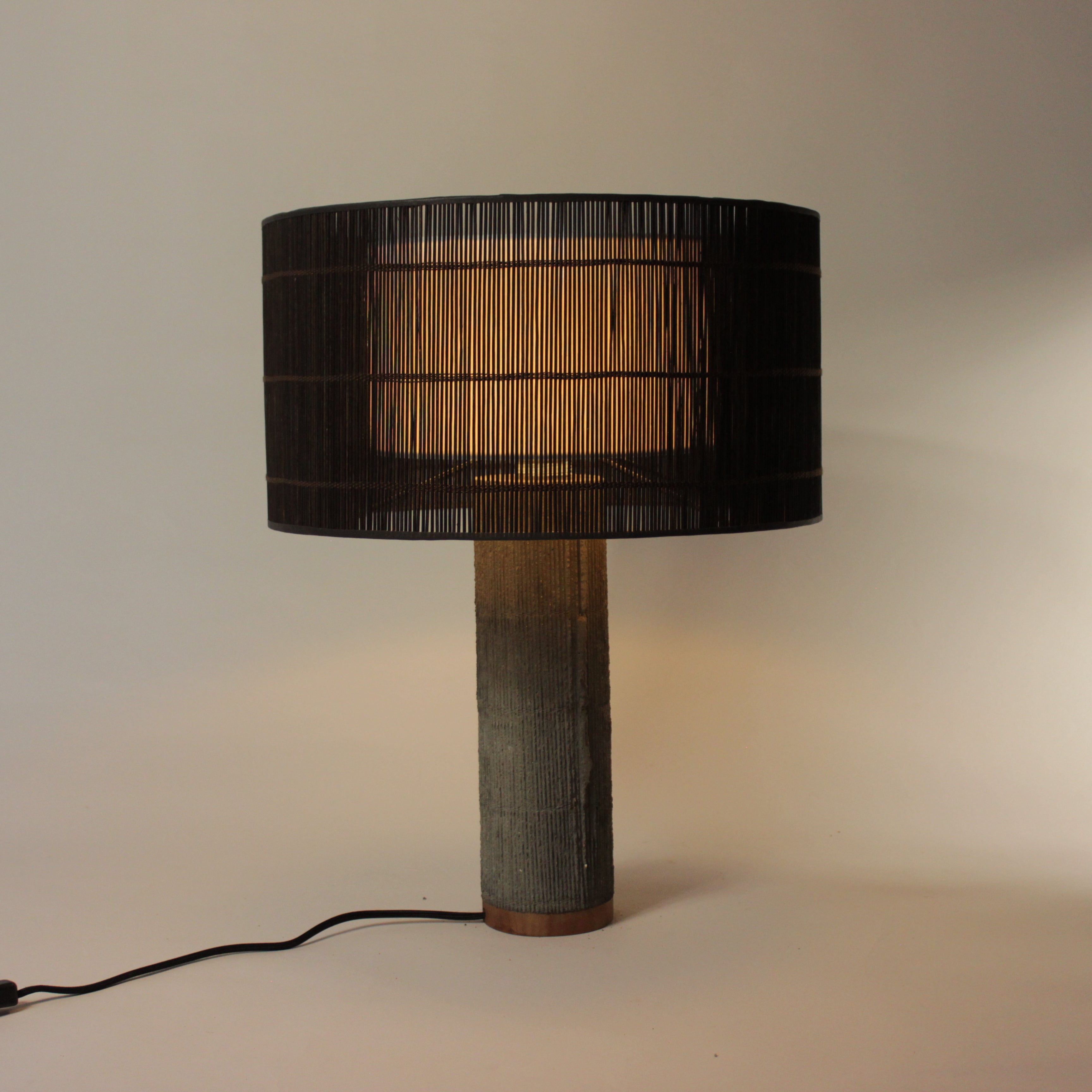 Stijlvolle lamp met donkerbruine geweven kap en betonnen voet in rustige tint.