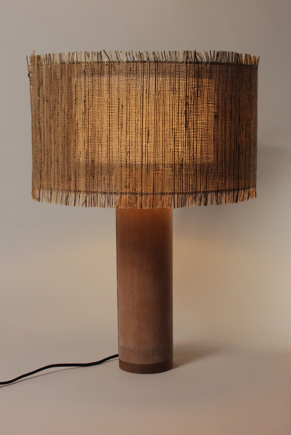 Elegante geweven lamp met terracotta betonvoet, straalt ambachtelijke warmte uit.