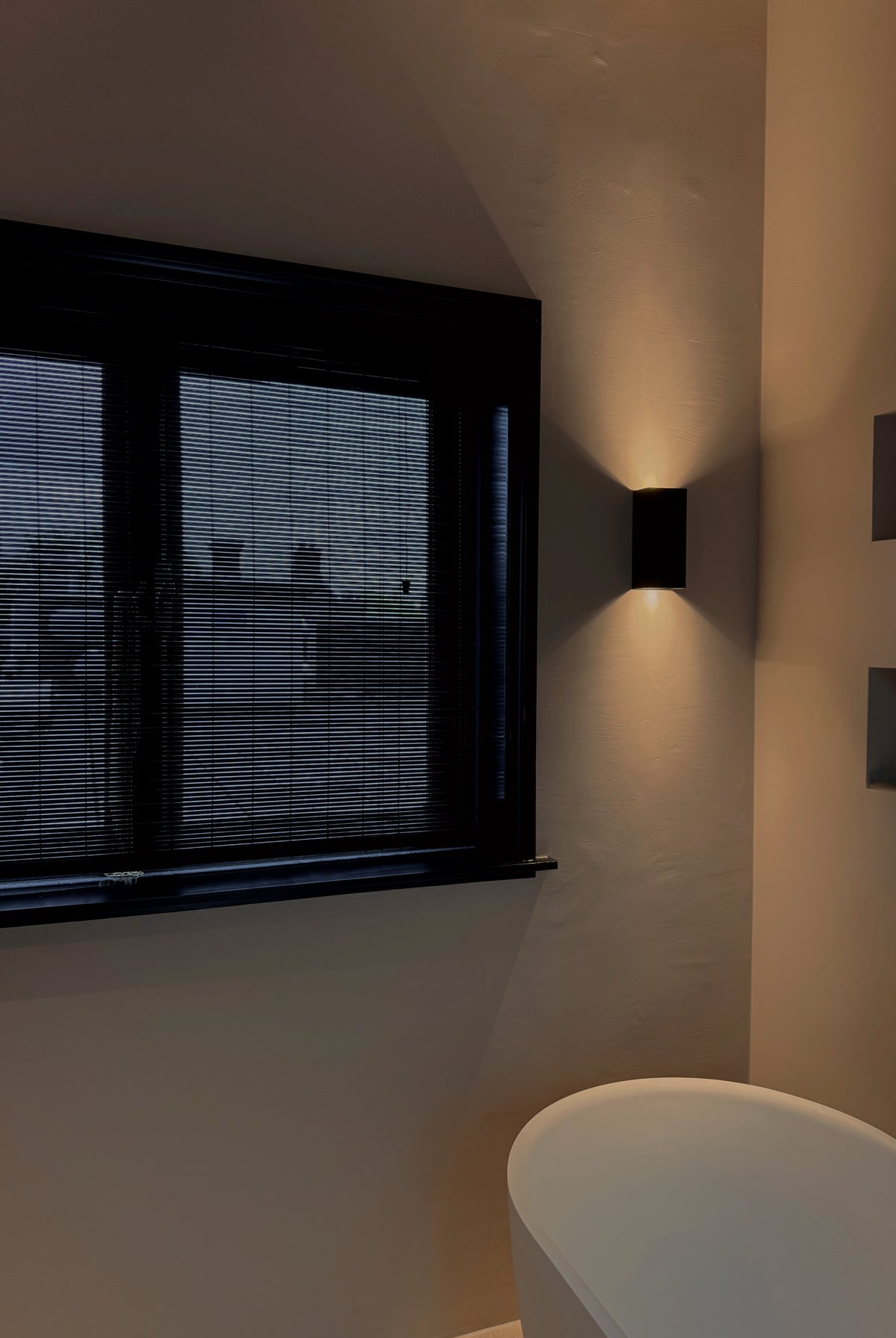 Moderne badkamer met Zwarte bamboo voor privacy en indirect licht tegen de muur.