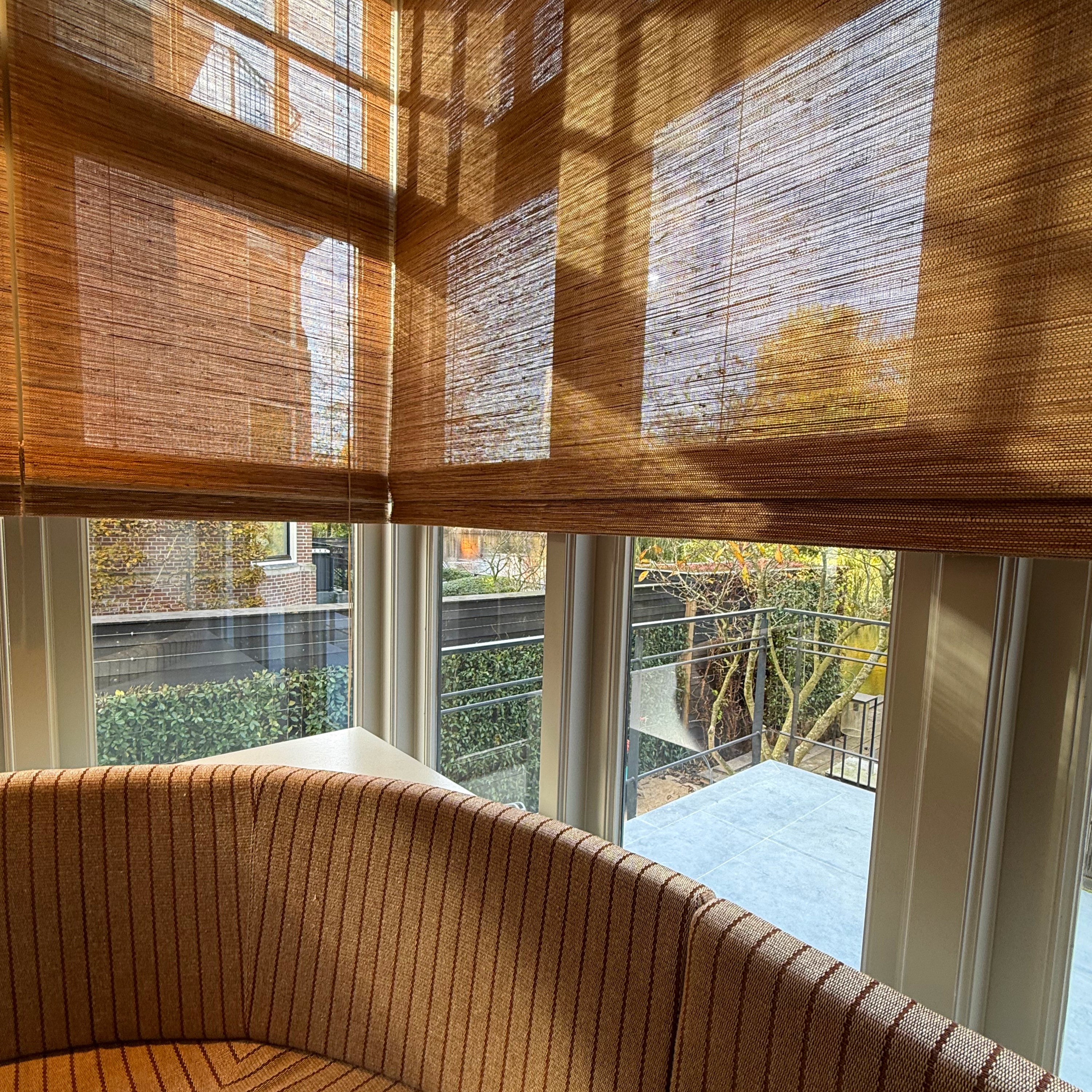 Folding Tuamoto blinds met natuurlijke lichtval en zachte schaduwen in een hoekraam.