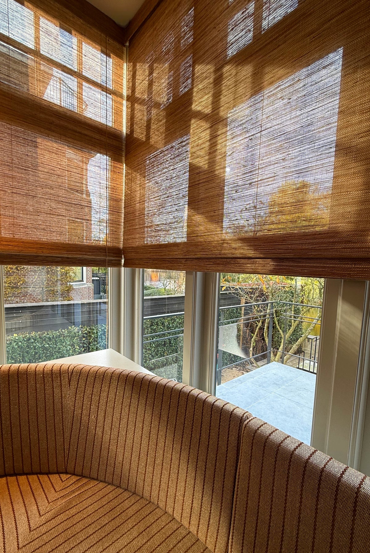 Folding Tuamoto blinds met natuurlijke lichtval en zachte schaduwen in een hoekraam.