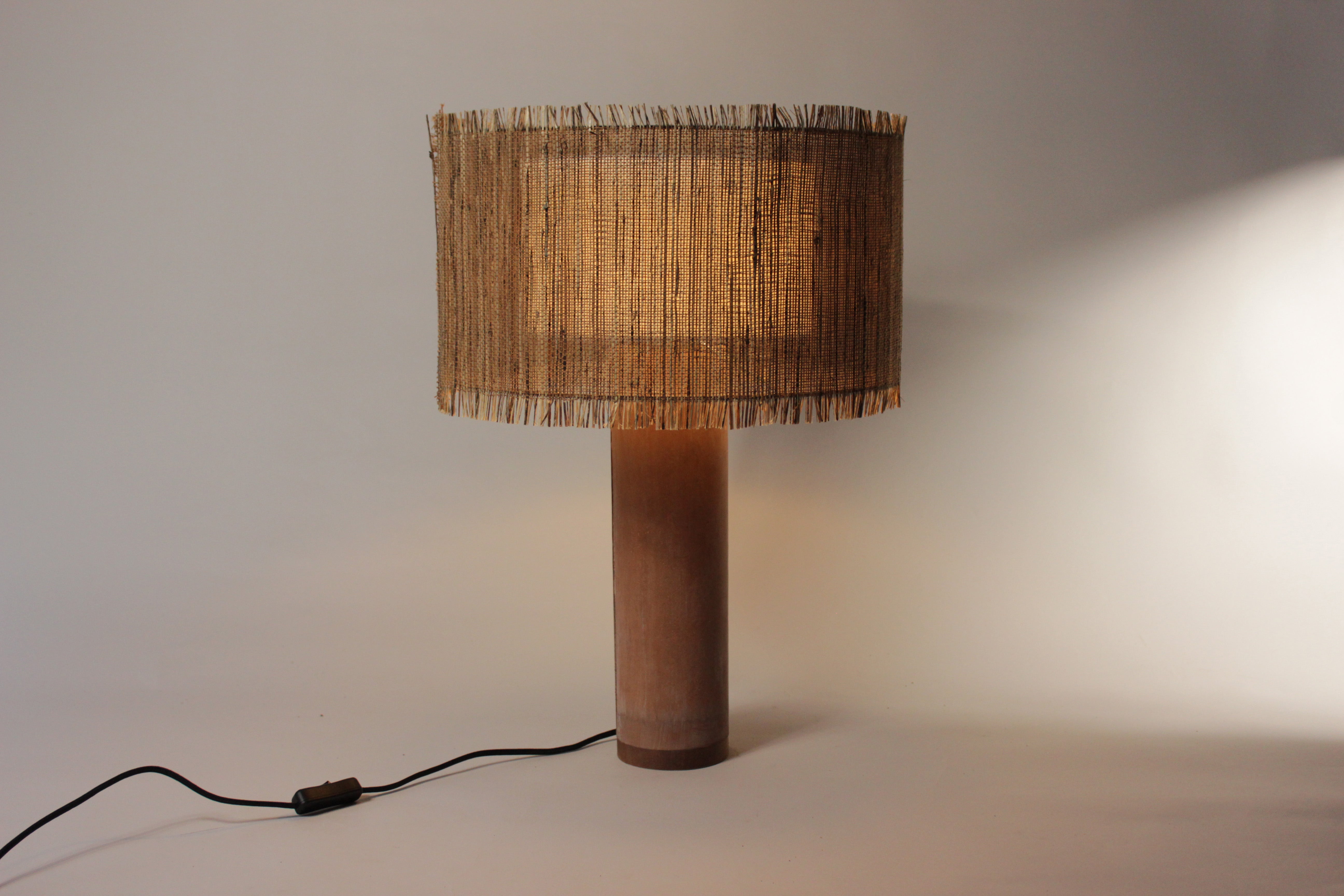 Elegante geweven lamp met terracotta betonvoet, straalt ambachtelijke warmte uit.