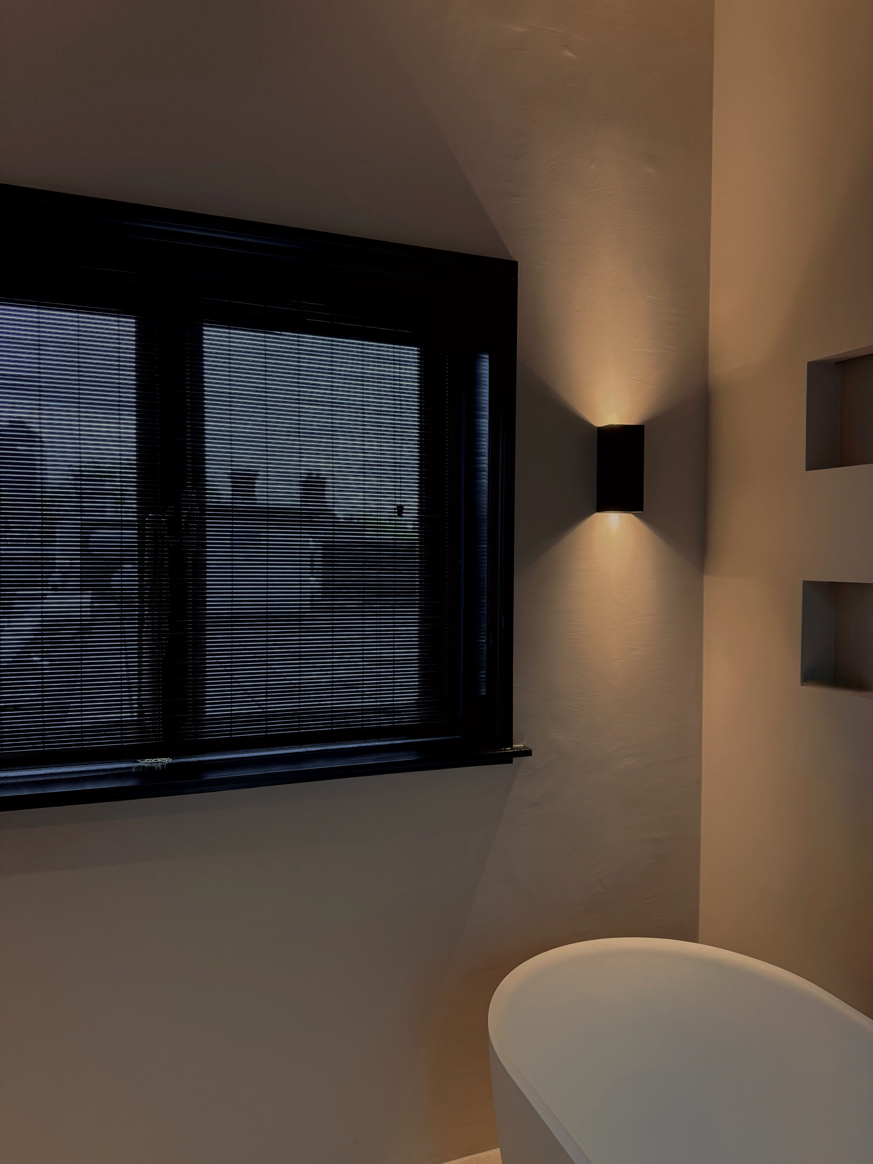 Moderne badkamer met Zwarte bamboo voor privacy en indirect licht tegen de muur.