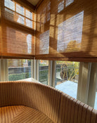 Folding Tuamoto blinds met natuurlijke lichtval en zachte schaduwen in een hoekraam.
