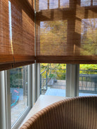 Vouwblinds van Tuamoto die zacht daglicht filteren met uitzicht op tuin en zithoek.