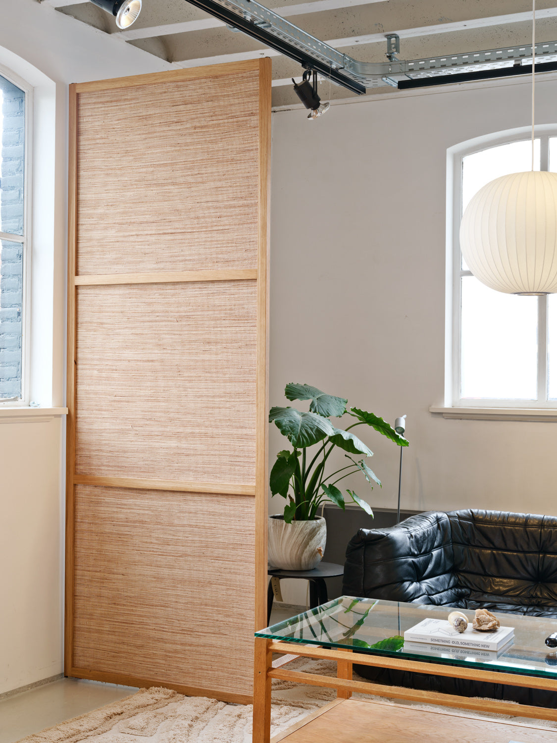 Noble Weave roomdivider van massief eikenhout als subtiele afscheiding in een woonkamer met natuurlijke materialen en zacht gefilterd licht.